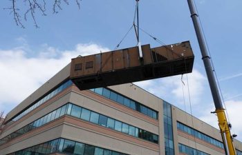 Big crane moving industrial HVAC unit.
